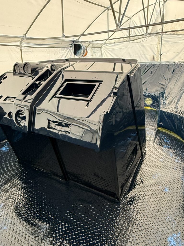 Angled view of a dark painted boat console with reflections and hardware openings visible