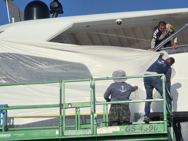 Sail ONYX crew placing protective sheeting along the Sunseeker exterior from an access platform