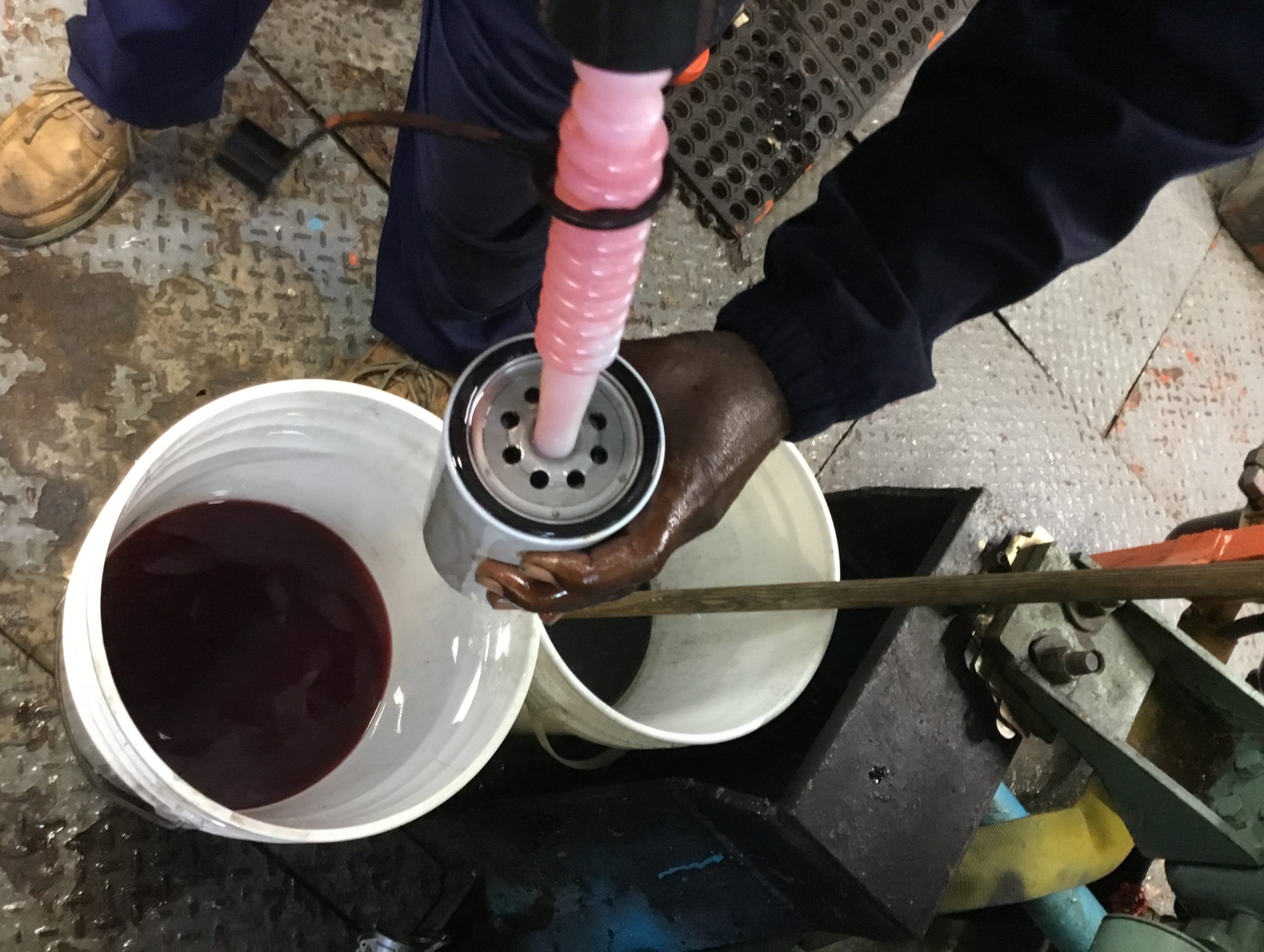 Technician servicing a marine diesel fuel filter in an engine room